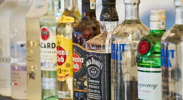 Różne rodzaje wódki i alkoholi, w tym Bacardi, Havana Club, Jack Daniel's, Absolut Vodka i Tanqueray, stoją w rzędzie.