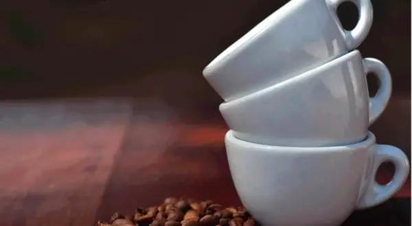 Tre tazzine bianche impilate e chicchi di caffè. Una tazzina di caffè contiene circa 60 ml.