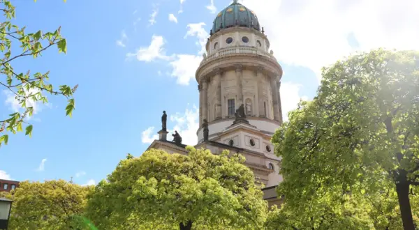 Der Dom in Deutschland, ein majestätisches Bauwerk, ragt hinter blühenden Bäumen in den blauen Himmel.