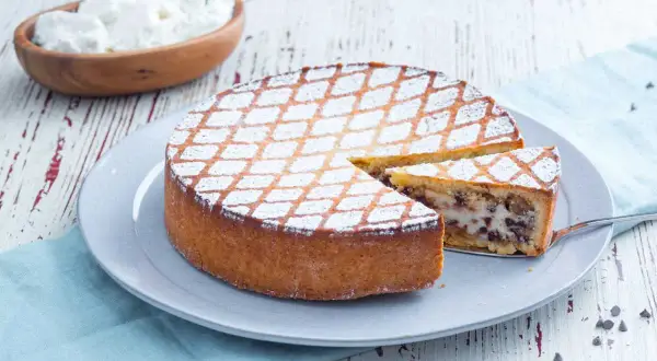 Une délicieuse cassata al forno, saupoudrée de sucre glace, avec une part coupée pour révéler sa garniture crémeuse et chocolatée.