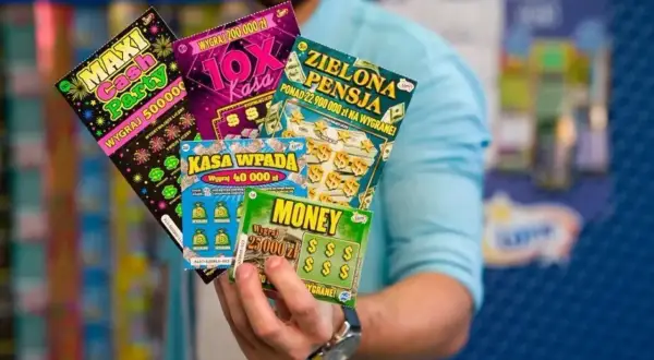 Dłoń trzyma kilka zdrapek Lotto z różnymi nazwami i kwotami wygranych.