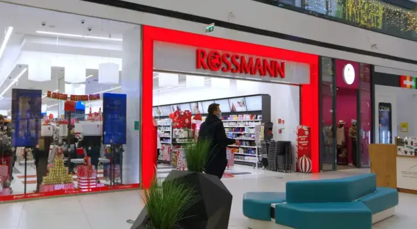 Wejście do drogerii Rossmann w centrum handlowym, z widocznymi promocjami i wystrojem świątecznym.
