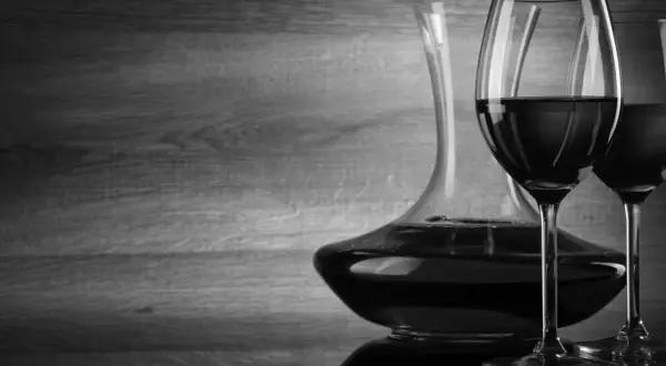 Caraffa e due calici di vino rosso, con un'atmosfera che evoca un buon cannellino di Frascati.