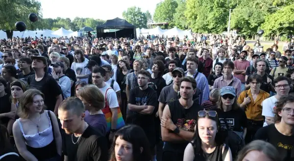 Tłum ludzi na koncercie w Katowicach. Słońce, drzewa i namioty festiwalowe w tle. Atmosfera festiwalu Katowice Off Festival.
