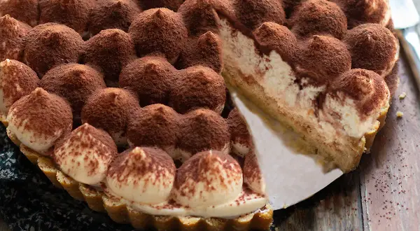 Una deliziosa torta tiramisù, con ciuffi di crema e cacao, pronta per essere gustata.