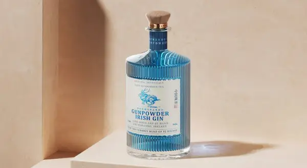 Elegancka butelka Drumshanbo Gunpowder Irish Gin, z niebieskim płynem i wytłoczonym jelonkiem, idealna na prezent dla miłośników ginów.