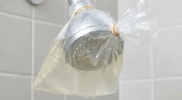 Doccia con soffione avvolto in un sacchetto pieno di liquido, per rimuovere residui di autoabbronzante che si toglie con l'acqua.