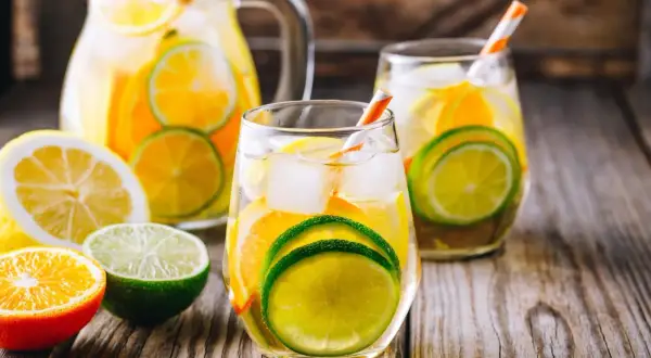 Orzeźwiająca biała sangria z plasterkami cytryny, limonki i pomarańczy, podana z lodem w szklankach i dzbanku.