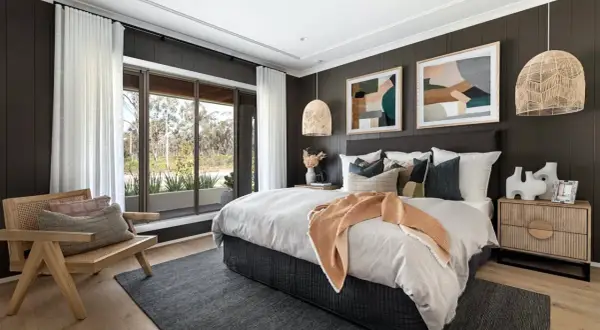 Light wood nightstands complement the dark wood bed. A cozy bedroom with a large window, rattan chair, and abstract art.