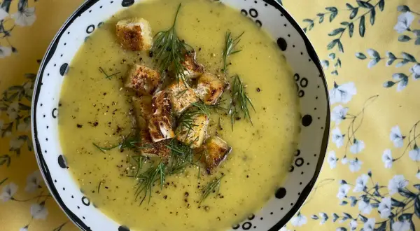 A miseczce zupy ogórkowej, ozdobionej grzankami i koperkiem, widać jak zaprawić zupę ogórkową.