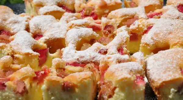 Puszyste ciasto z rabarbarem, posypane cukrem pudrem. Idealne na letnie popołudnie, gdy masz ochotę na domowy **przepis na ciasto z rabarbarem**.