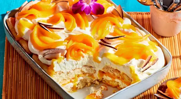 Ein cremiges Mango Tiramisu mit Kokosflocken und einer exotischen Orchidee verziert.