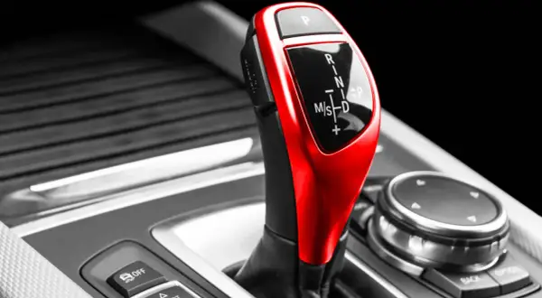Roter Automatikschalthebel mit Ganganzeige (P, R, N, M/S, D) in einem Auto.