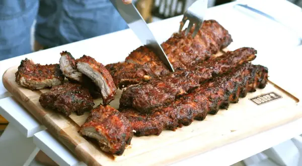 Grillade kamben skärs upp på en skärbräda. Saftiga och rökiga, redo att avnjutas.