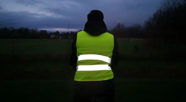 Person mit Warnweste Fahrrad im Dämmerlicht. Sichtbarkeit ist wichtig, auch wenn es nicht verboten ist.