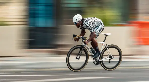 Dynamic racing photography captures a cyclist in motion, blurring the background to emphasize speed.