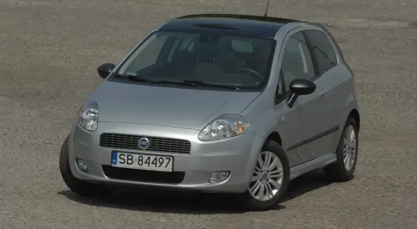 Srebrny Fiat Punto z czarnym dachem i przyciemnianymi szybami, z widocznymi światłami.