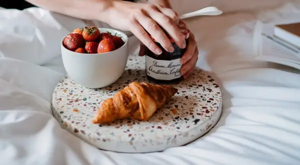Een croissant, aardbeien en confituur op een dienblad. Perfect om te genieten van eten uit verveling op een luie ochtend.