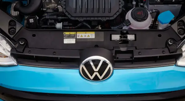 Motorutrymmet på en blå Volkswagen. En etikett visar information om olja och kylvätska, vilket kan vara relevant vid ett volkswagen gasbil problem.