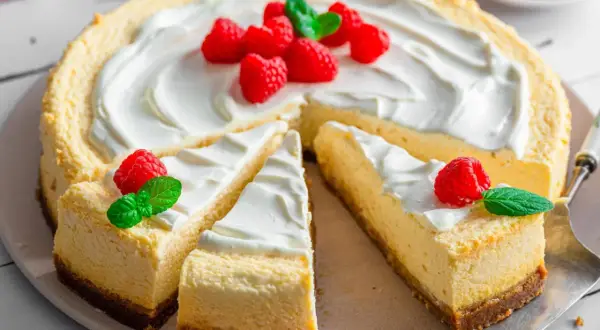 Ein köstlicher american cheesecake, dekoriert mit frischen Himbeeren und Minze, wartet darauf, genossen zu werden.