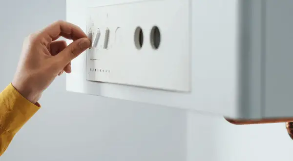 Main d'une personne ajustant le bouton d'une prime cee chaudière gaz.