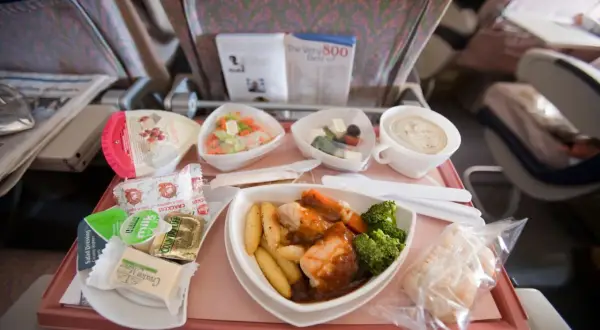 Ein Flugzeugessen mit Hähnchen, Kartoffeln, Brokkoli, Salat und einem Dessert. Guten Appetit beim Essen im Flugzeug!
