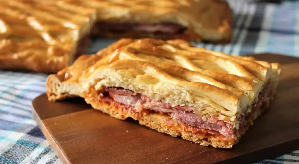 Un delicioso hornazo de Pascua, con su masa dorada y relleno de carnes, listo para compartir.