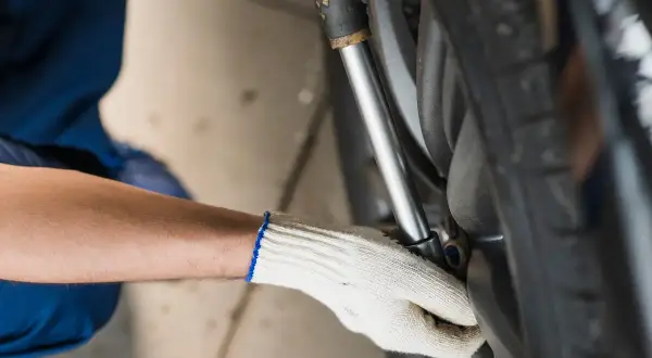 Mechanik w białej rękawicy dokręca śruby koła kluczem dynamometrycznym, dbając o to, z jaką siłą dokręcać koła.
