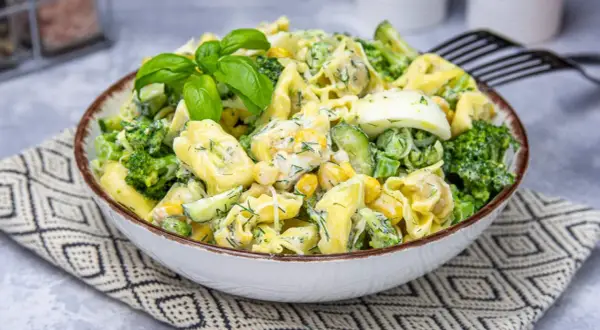 Pyszna sałatka z tortellini, brokułów, kukurydzy, ogórka i jajka w kremowym sosie.