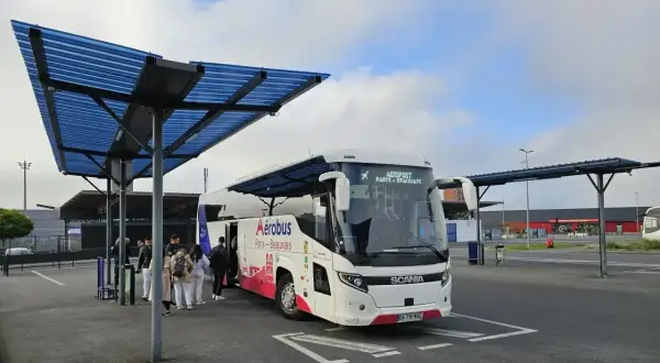 Autobus Aerobus z napisem "Paris-Beauvais" czeka na pasażerów pod niebieskim zadaszeniem.