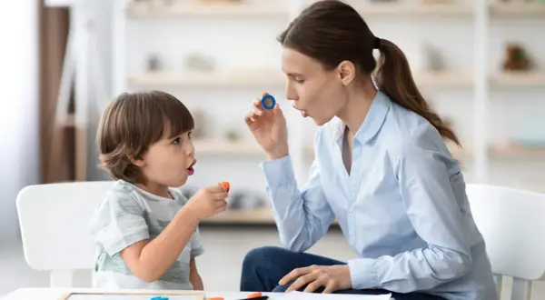Terapeuta enseña trabalenguas para niños usando piezas de letras.