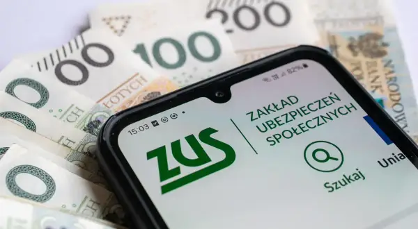 Telefon z aplikacją ZUS na tle polskich banknotów. Sprawdź, czy zasiłek dla bezrobotnych wlicza się do emerytury.