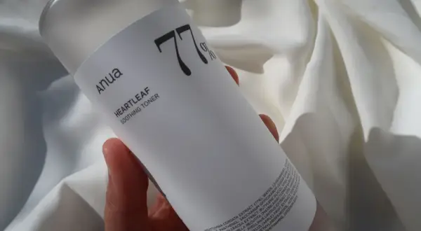 Anua Heartleaf Soothing Toner 77% w dłoni na tle białej tkaniny. Idealny do codziennej pielęgnacji.