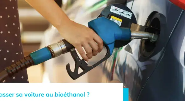 Main d'une personne tenant un pistolet de pompe à essence pour faire le plein d'une voiture. Recherche d'une liste voiture compatible e85 sans kit pour rouler plus vert.