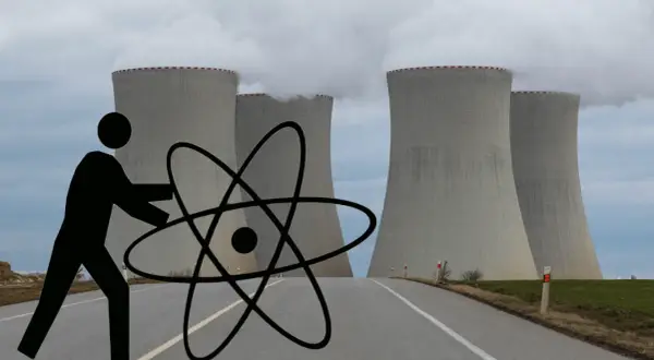 Człowiek z atomem przed chłodniami kominowymi elektrowni jądrowej symbolizuje potencjalne wady elektrowni jądrowej.