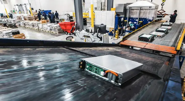 Proces utylizacji baterii samochodów elektrycznych. Baterie na taśmie produkcyjnej, pracownicy w tle.
