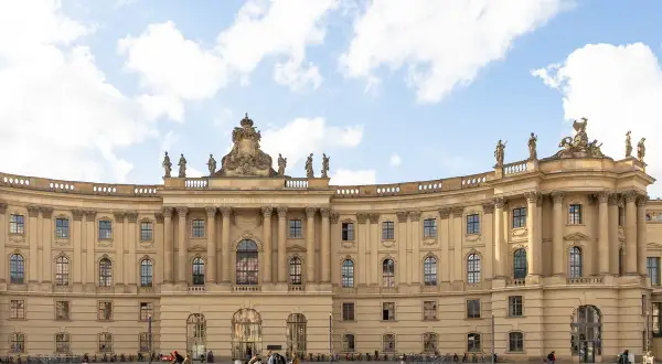 Humboldt-Universität zu Berlin, eine der besten Architekturen von Unis in Deutschland, mit imposanter Fassade und Studenten auf dem Platz.