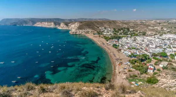 Vista aérea de la costa con aguas turquesas, barcos y el pueblo blanco de restaurante costamarga.