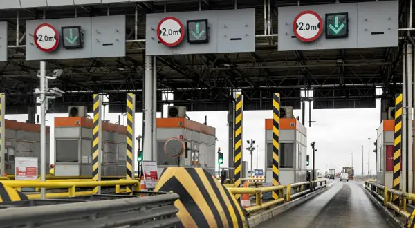 Płatne autostrady w Polsce: szlabany na bramkach poboru opłat, znaki ograniczenia wysokości 2,0m i zielone strzałki wskazujące otwarte pasy ruchu.