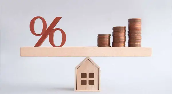 Bilancia con simbolo percentuale e pile di monete su una casa. Un'illustrazione su come comprare una casa.