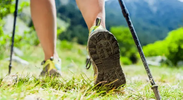 Wanderer mit Trekkingstöcken im Gebirge. Nach Krebserkrankung nicht mehr belastbar, aber die Natur gibt Kraft.