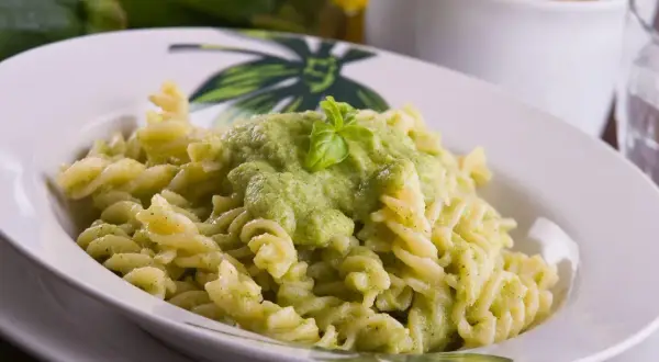 Fusilli z kremowym, zielonym sosem z cukinii, udekorowane listkiem bazylii. Pyszny sos z cukinii do makaronu.