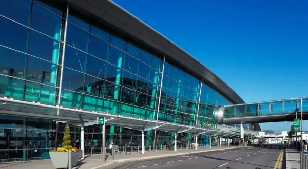 Nowoczesny terminal lotniska w Irlandii, z przeszkloną fasadą i mostem łączącym budynki.