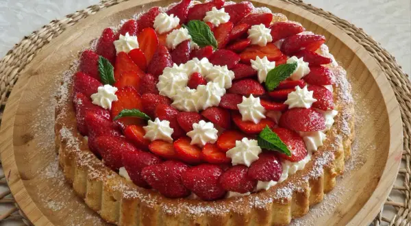 Un délicieux biscuit pour fraisier, garni de fraises fraîches, de crème fouettée et de feuilles de menthe.