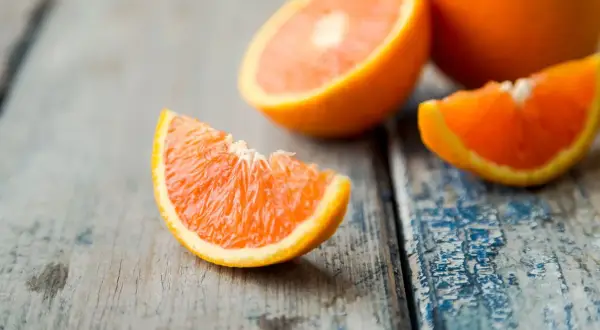Arance fresche tagliate a spicchi su un tavolo di legno. Quante arance si possono mangiare al giorno per un pieno di vitamina C?