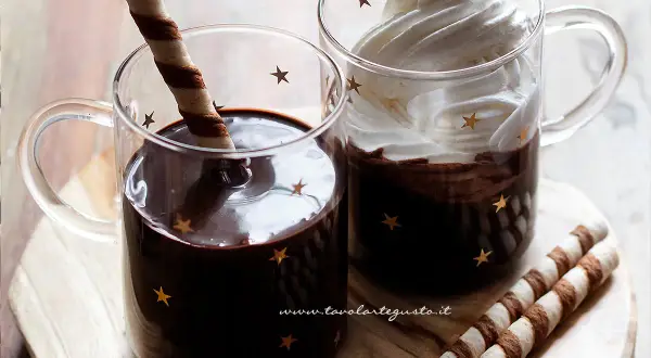 Due tazze di cioccolata calda con cacao e latte, una con panna e cacao, l'altra con un biscotto.
