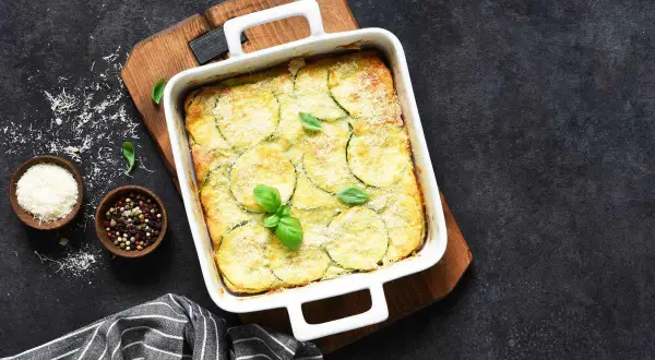 Sformato dorato con zucchine e patate, guarnito con basilico fresco. Un'idea gustosa per le tue ricette con zucchine e patate.