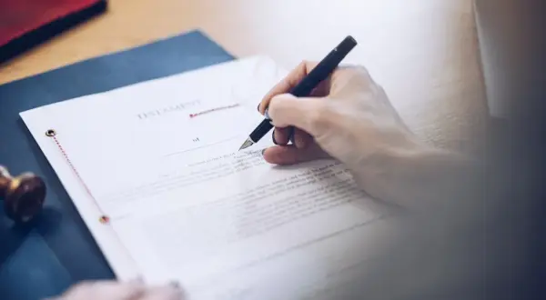 Dłoń pisze piórem na dokumencie testamentu. To ważny testament allograficzny, który określa przyszłość.