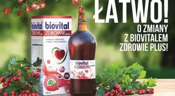 Biovital Zdrowie Plus – suplement diety z głogiem i witaminami. Pudełko i butelka na drewnianym stole, otoczone gałązkami z czerwonymi owocami.