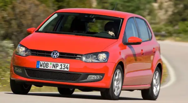 Czerwony vw polo 2010 na zakręcie drogi.